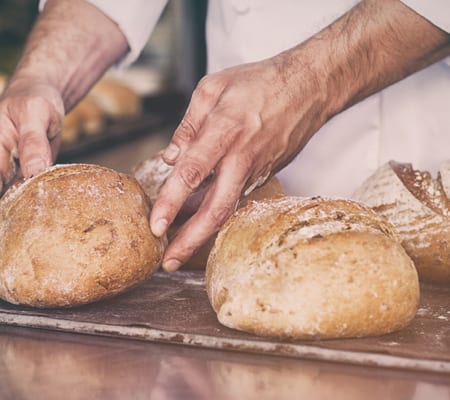 Baker shaping rustic sourdough loaves on a wooden board